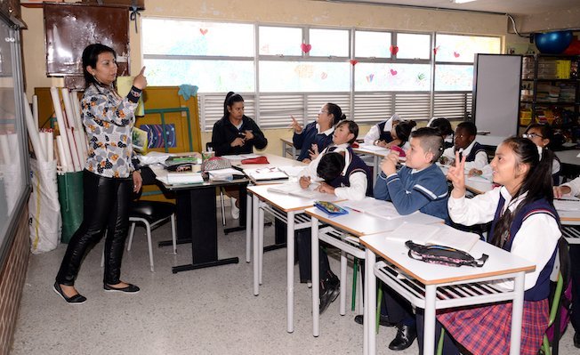 Maestra y estudiantes sordos en un aula escolar usando lengua de señas